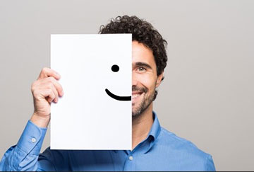 Young man holding a paper to his face with half a smile