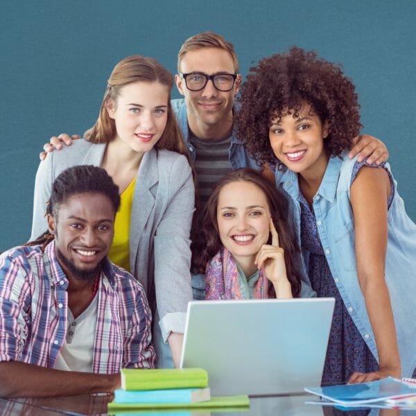 Happy classmates using laptop on table