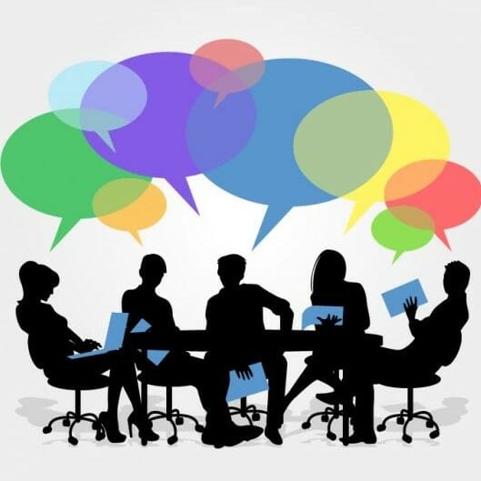 Speech bubbles floating above people engaged in a meeting