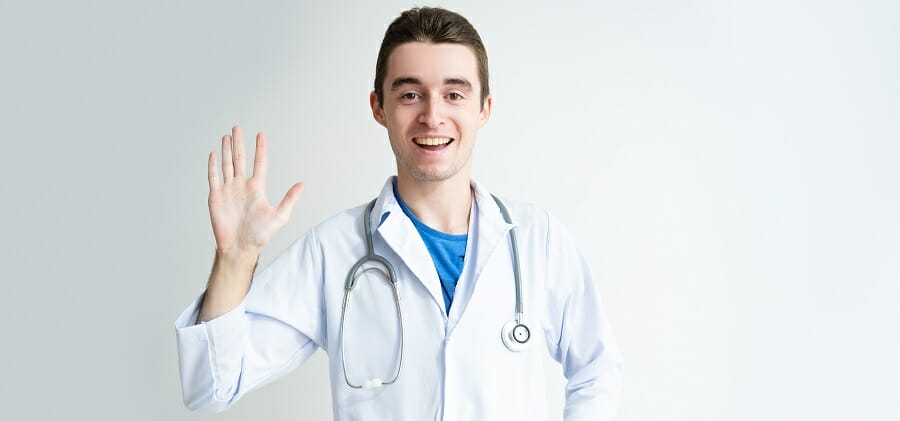 Friendly young male doctor waving hand