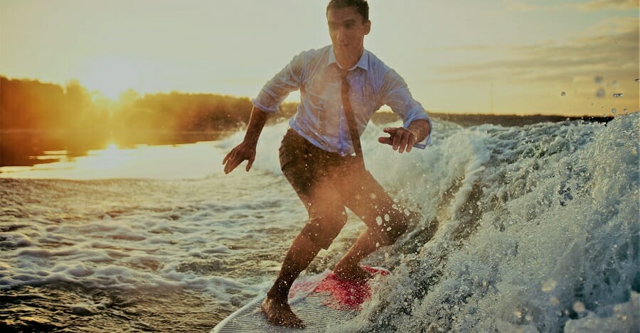 Young man in wet clothes surfboarding at summer resort