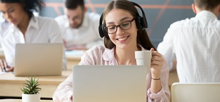 Smiling woman wearing headphones watching online video during co