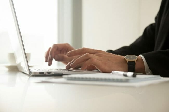 Close up image of mans hands in wristwatch typing on laptop Close up image of mans hands in wristwatch typing on laptop
