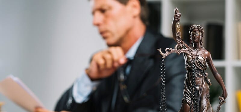 Close of up of statue of lady justice with man in background