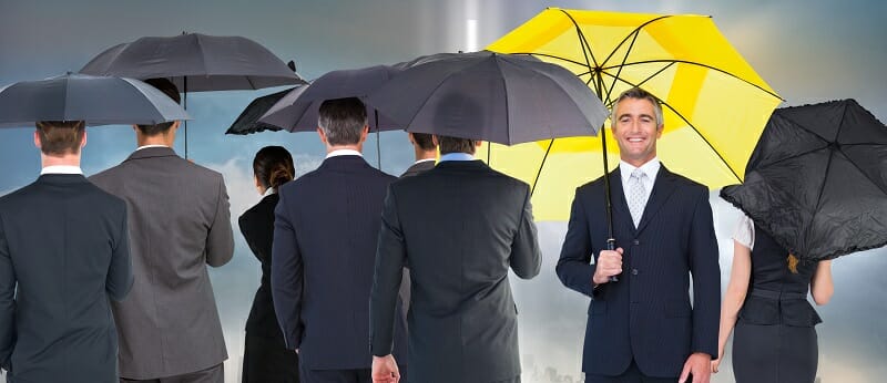 Older male with a yellow umbrella standing out in a crowd