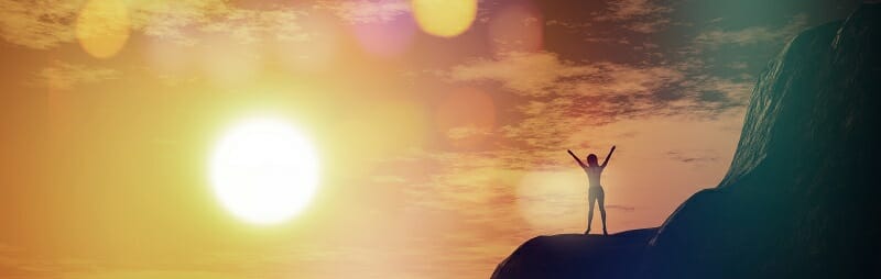 3D female on top of a cliff against a sunset sky