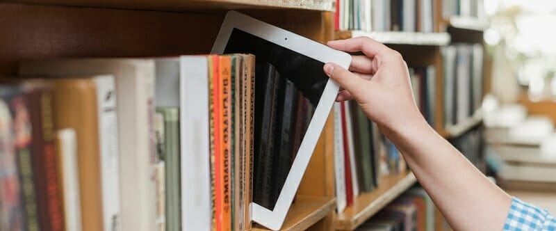 Student taking iPad off bookshelf