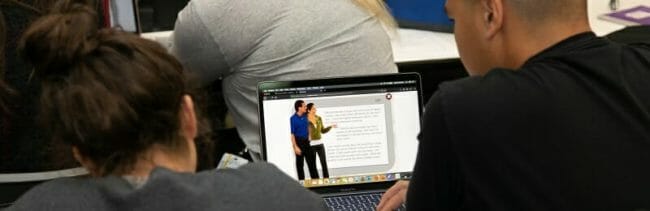 Students looking at case study on laptop