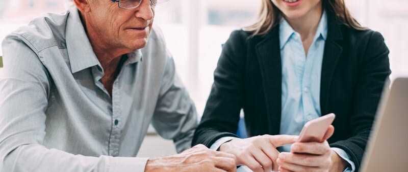Smiling businesswoman showing phone to colleague