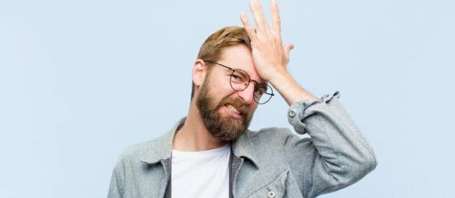 raising palm to forehead thinking oops, after making a stupid mistake or remembering, feeling dumb Young blonde man raising palm to forehead thinking oops, after making a stupid mistake or remembering, feeling dumb
