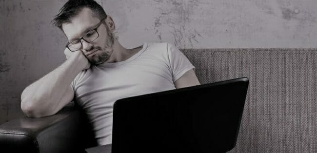 The guy in the white shirt sitting on the couch, fell asleep at work on a laptop. The concept of laziness, apathy, frustration, procrastination, the person at home. copy space.