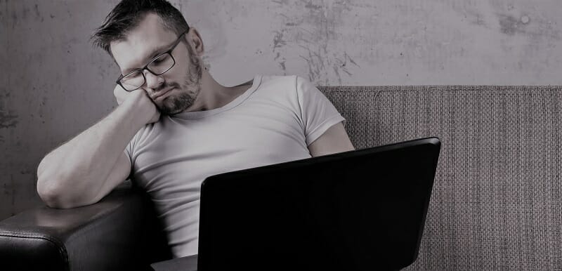 The guy in the white shirt sitting on the couch, fell asleep at work on a laptop. The concept of laziness, apathy, frustration, procrastination, the person at home. copy space.